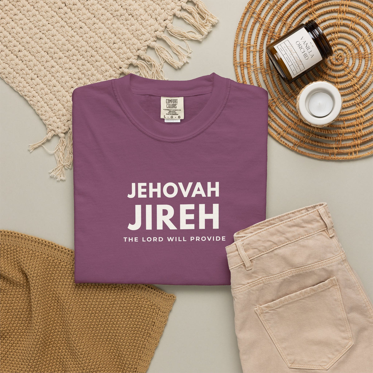berry purple Jehovah Jireh Christian T-shirt with “The Lord Will Provide” typography, styled in a neutral flat lay.