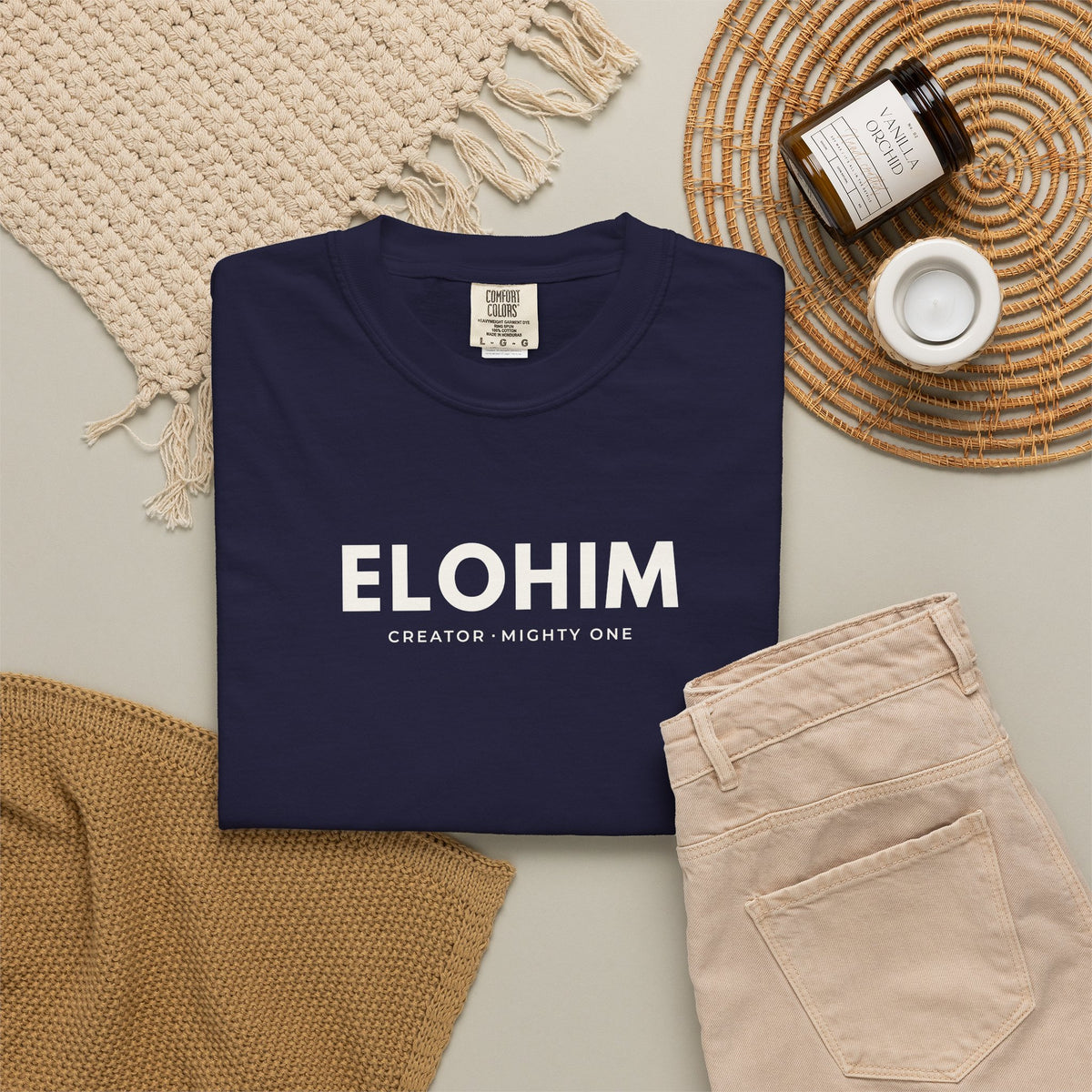 True navy Elohim Christian T-shirt with “Creator · Mighty One” typography, styled in a neutral flat lay.
