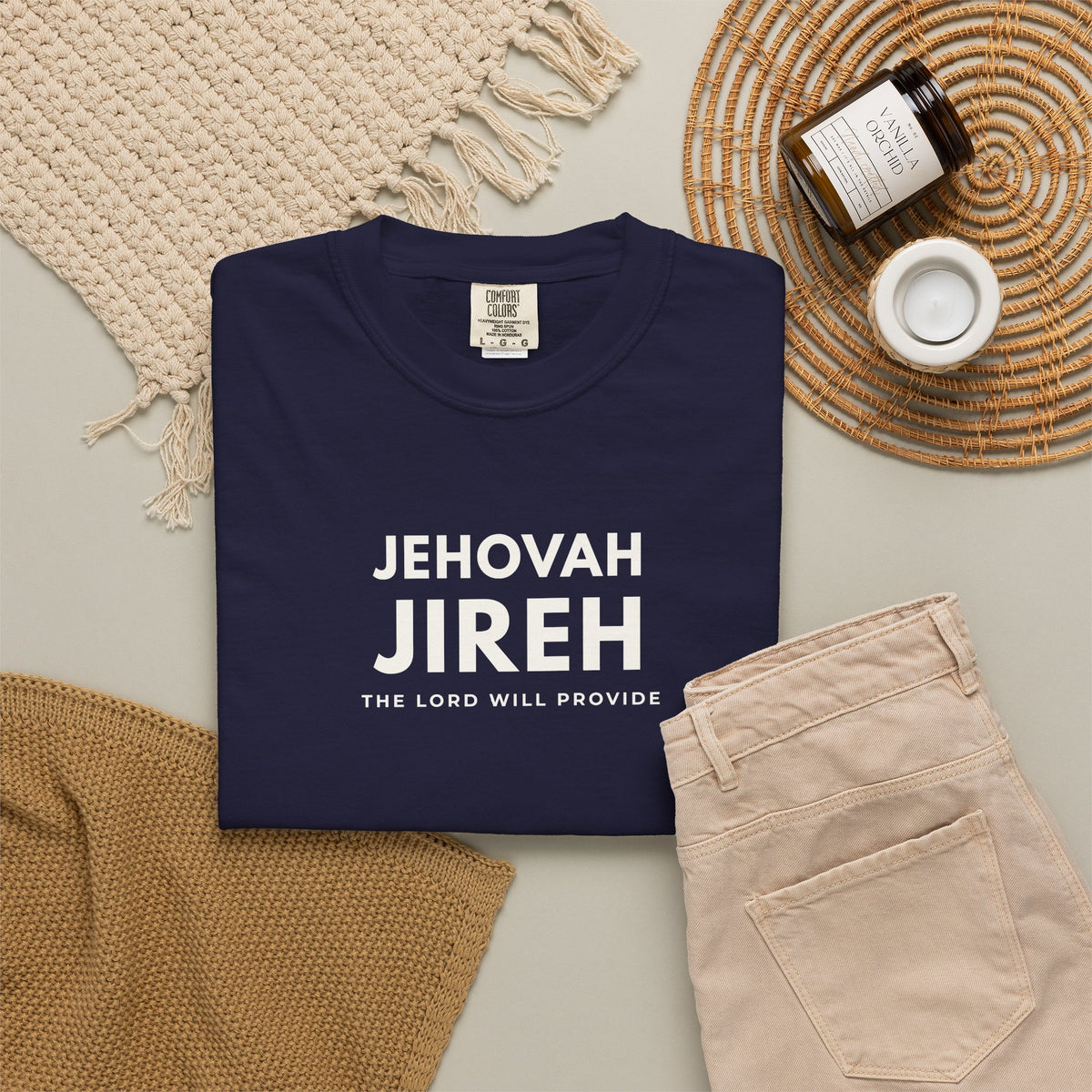 True navy Jehovah Jireh Christian T-shirt with “The Lord Will Provide” typography, styled in a neutral flat lay.