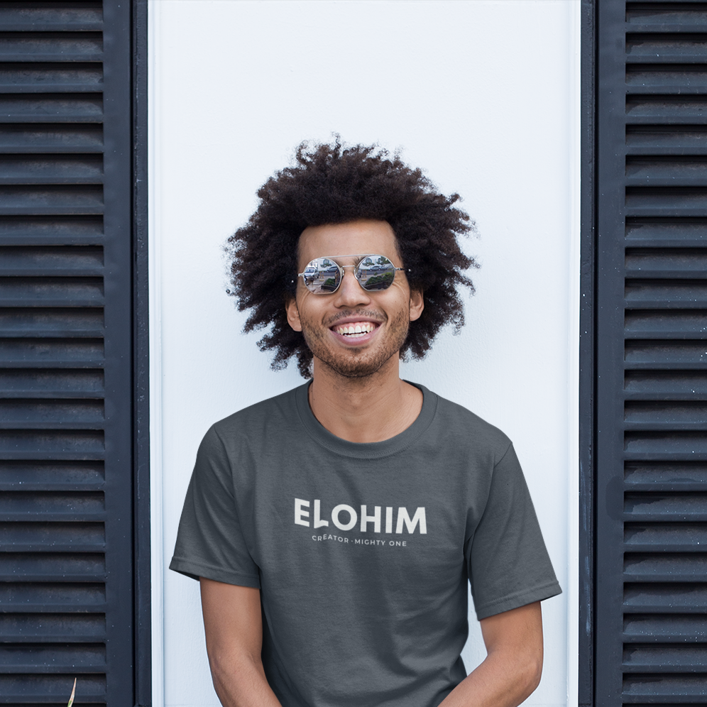 Smiling man wearing sunglasses and a grey Elohim Christian T-shirt with “Creator · Mighty One” printed in white.